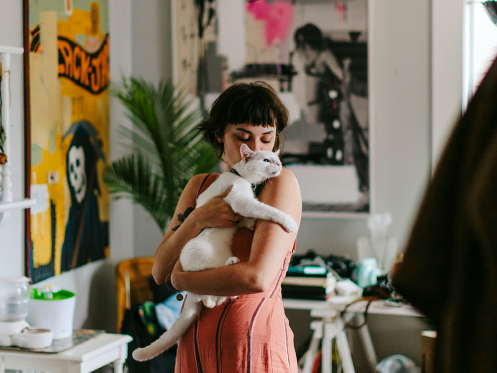 Woman holding cat wearing collar in hip apartment